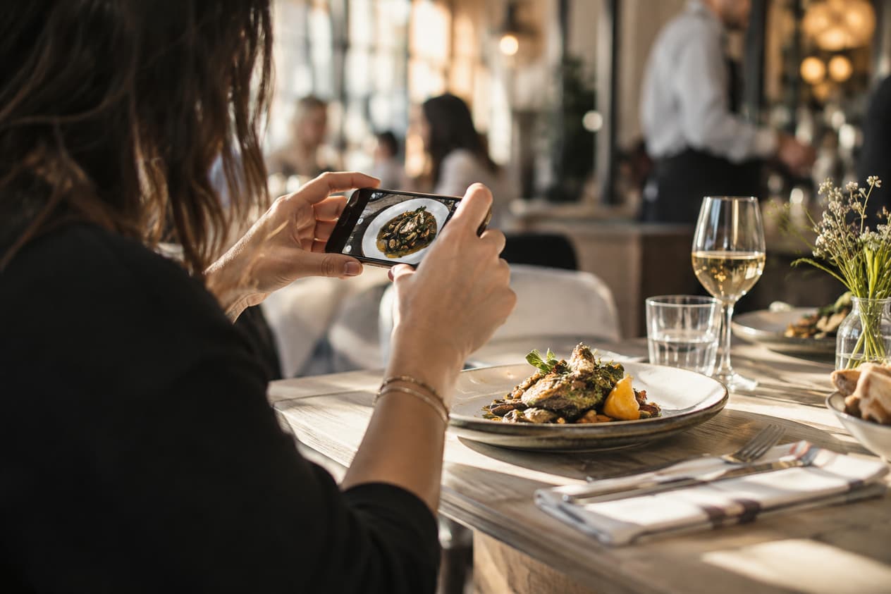 Photographie d’un plat au téléphone dans une salle de restaurant