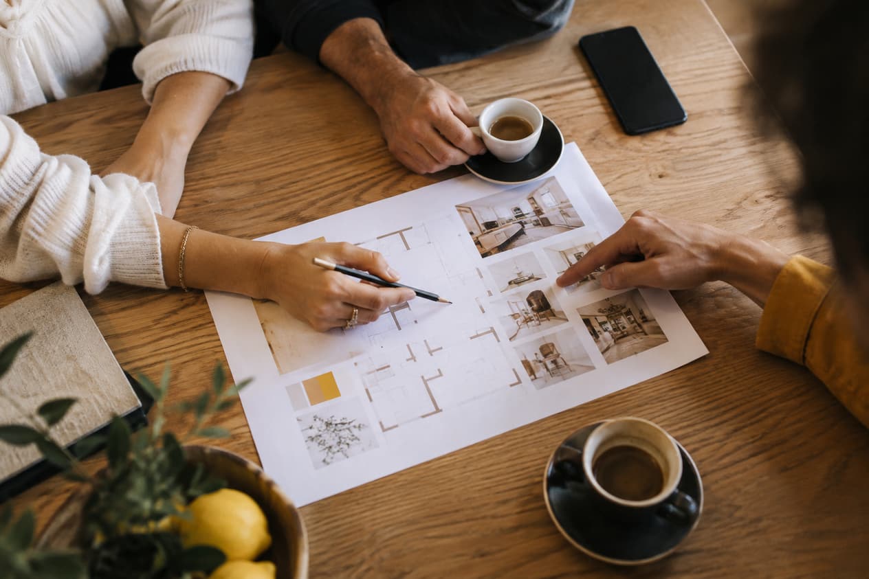 Trois personnes autour d’un plan de travail papier et de deux cafés