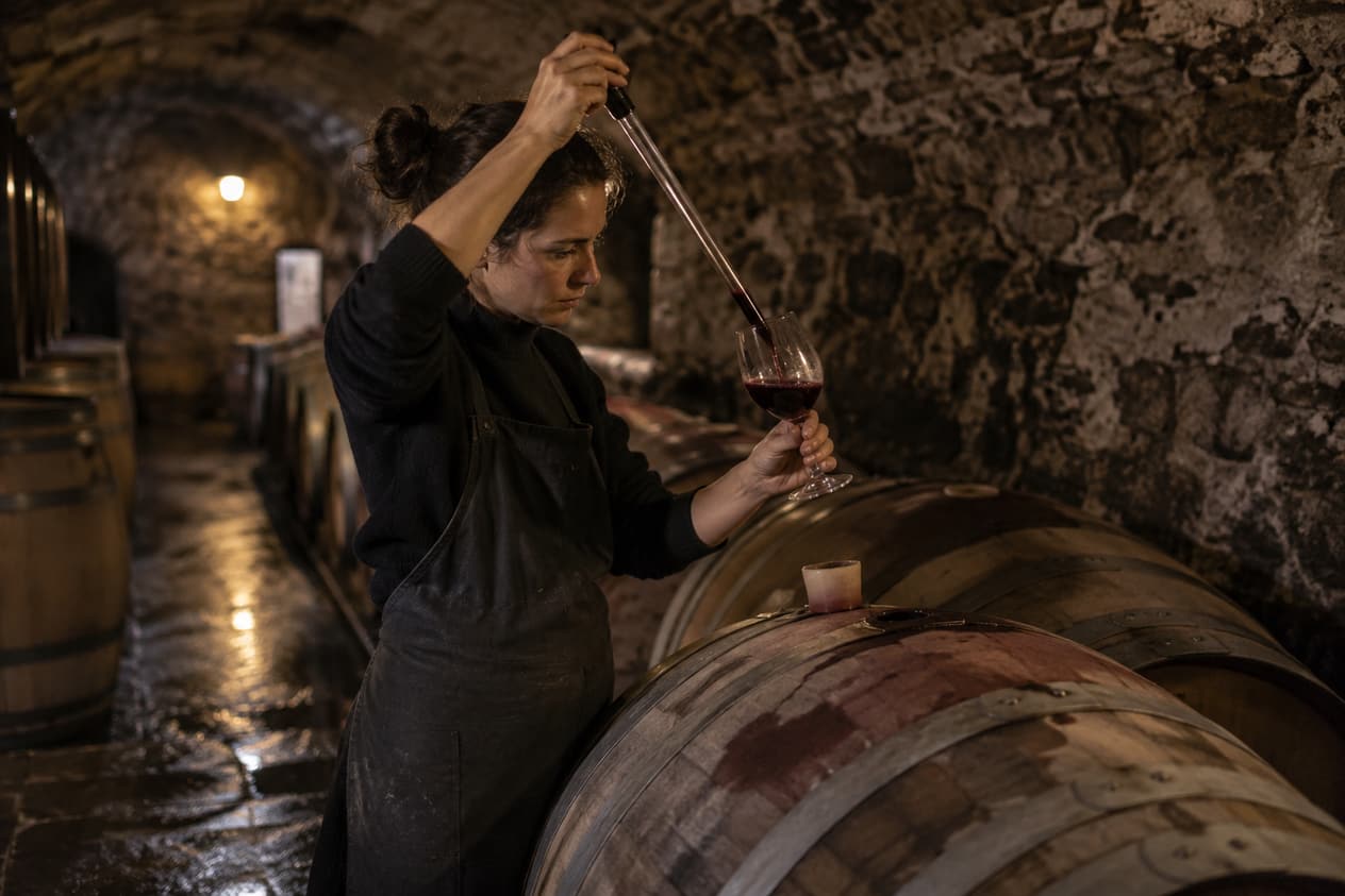 Un vigneron prélève un échantillon à la pipette dans son chai